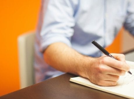 man writing in notebook