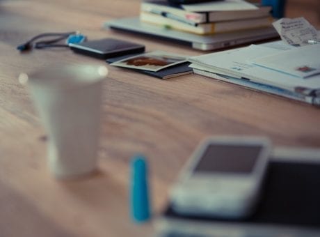 desk with phone, cup and notebooks