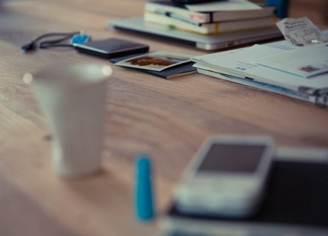 desk with phone, cup and notebooks