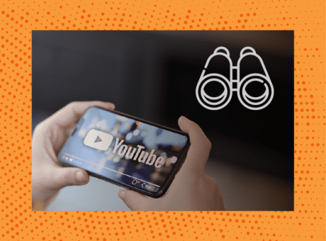 Two hands hold a smartphone with YouTube on it. Binoculars are in the upper right corner of the image.